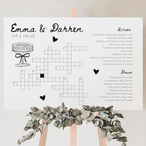 Pu&ograve; includere: Un cruciverba di matrimonio stampabile in bianco e nero con il titolo "Emma & Darren Sip & Solve". Il cruciverba presenta un'illustrazione di un bicchiere di champagne e cuori.