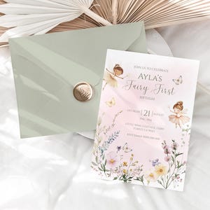 Pu&ograve; includere: Una busta verde salvia con un sigillo in ceralacca dorata con l'impronta di una foglia, abbinata a un invito di compleanno rettangolare. La carta mostra illustrazioni di fate, farfalle e fiori di campo con il testo: JOIN US TO CELEBRATE AYLA'S Fairy First BIRTHDAY SATURDAY 21 AUGUST 3PM-5PM LITTLE WING COTTAGE, FAIRY FOREST CA 90210 RSVP EMMA 000 000 000.