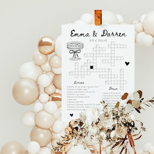 Pu&ograve; includere: Un gioco di cruciverba stampabile con il titolo "Emma & Darren Sip & Solve". Il cruciverba &egrave; circondato da uno sfondo bianco con un arco di palloncini decorativo sullo sfondo.