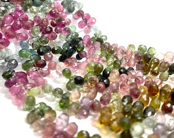 May include: A strand of faceted gemstone beads in various shades of pink, green, and black. The beads are oval-shaped and have a smooth, polished finish.
