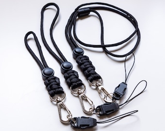 Könnte beinhalten: Drei schwarze Lanyards mit silbernen Verschlüssen und schwarzen Plastikclips. Die Lanyards sind aus geflochtenem Kordel und haben ein schlichtes Design.