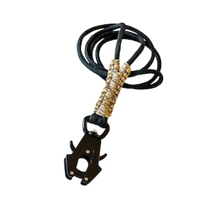 May include: A black and tan paracord leash with a black metal clip. The leash is made with a braided paracord design.