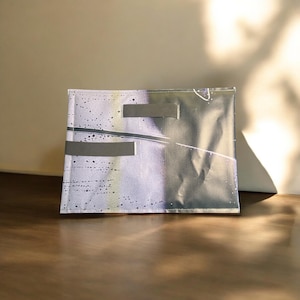 May include: A small, rectangular pouch with a black and white abstract design. The pouch is made of a soft, textured fabric and has a zipper closure.