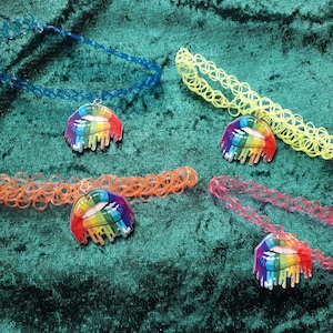 Op de afbeelding: Vier kleurrijke plastic choker kettingen met regenboog-lip hangers. De chokers zijn in blauw, geel, oranje en roze.
