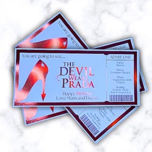 May include: Several light blue tickets with a red and silver design. The tickets feature the text "The Devil Wears Prada" and a high-heeled shoe graphic. The tickets are for a theatre performance.