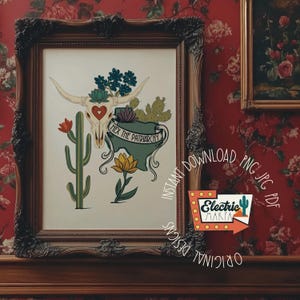May include: A framed art print featuring a cow skull with a heart, cacti, and the text "Hex the Patriarchy." The artwork is in a dark wooden frame, with a floral background. The print has a vintage, southwestern aesthetic.