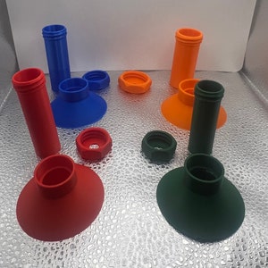 Puede incluir: Surtido de embudos y tapas de plástico de colores. Los embudos son azules, verdes, naranjas y rojos. Las tapas son azules, verdes, naranjas y rojas.