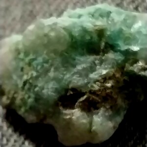 May include: A close-up of a green and brown rock with a rough, textured surface.