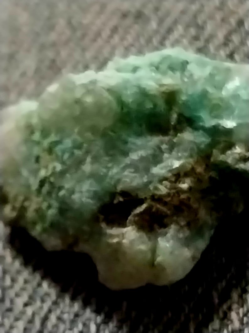 May include: A close-up of a green and brown rock with a rough, textured surface.