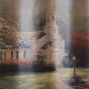 May include: A painting of a church with a steeple, surrounded by trees and greenery. The artwork features a pathway leading to the church, with a soft, muted color palette. The scene evokes a sense of tranquility and nostalgia.