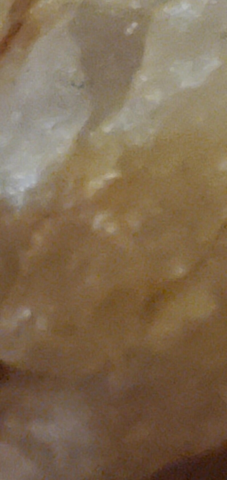 May include: Abstract close-up of a textured surface with a blend of light and dark brown tones. The surface has a mottled appearance with lighter, off-white patches scattered throughout, creating a natural, organic aesthetic.