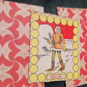 May include: A vintage game card featuring a cartoon illustration of a person wearing a fur-trimmed coat and snowshoes. The card has a yellow border with a red background and the word "MERCURY" printed at the bottom.
