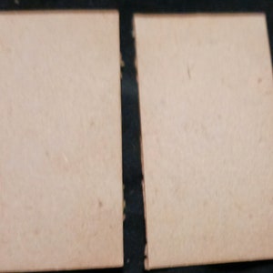 May include: Two blank, light brown, rectangular cards.
