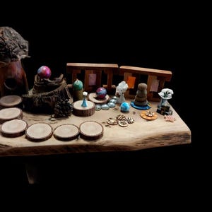 May include: A rustic wooden table displays a collection of miniature decorative items. The arrangement includes wooden coasters, small sculptures, colorful spheres, and a wooden structure, all set against a black background.
