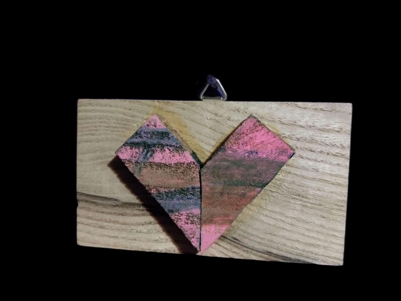 May include: A wooden heart-shaped wall hanging with a pink and purple painted design.