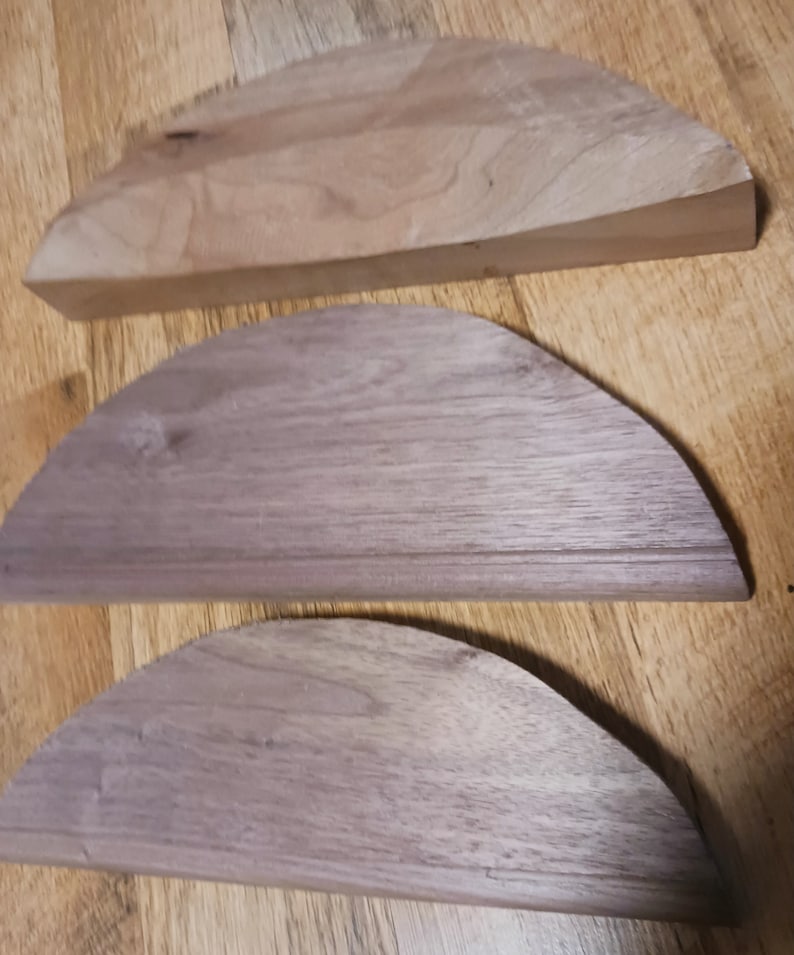 May include: Three wooden half-circle shapes, the top one is flat and the bottom two are curved. The wood is a light brown color.