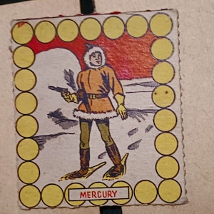 May include: A vintage game card featuring a cartoon illustration of a person wearing a fur-trimmed parka and snowshoes, holding a gun. The card has a yellow border with a circle pattern and the word "MERCURY" printed at the bottom.