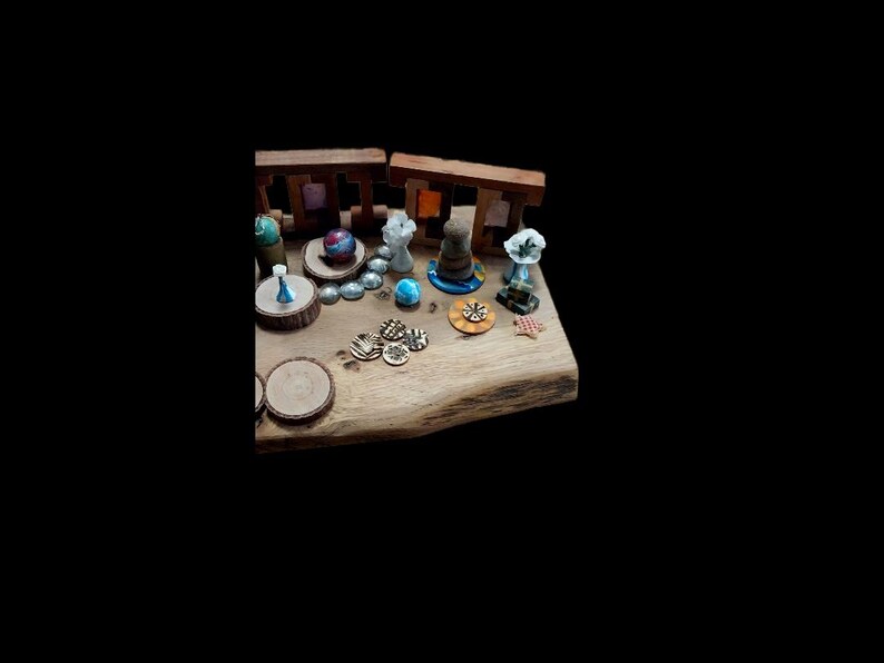 May include: A wooden display featuring miniature decorative items. Includes small sculptures, wooden rounds, and colorful glass beads. The items are arranged on a natural wood surface, with a dark background.