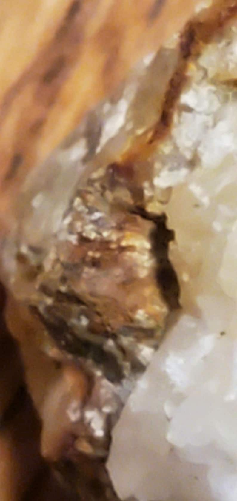 May include: Close-up of a natural mineral formation with a mix of colors. The image shows a combination of brown, tan, and white hues, with a textured surface. The mineral appears to be crystalline in structure.