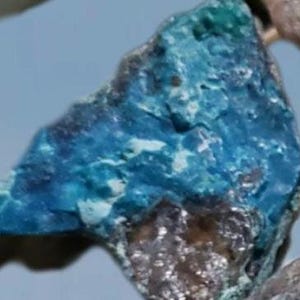 May include: A close-up of a blue and white mineral specimen. The mineral has a rough, textured surface and a variety of shades of blue.