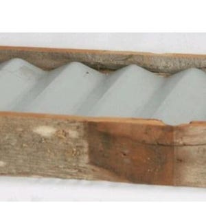 May include: A rectangular wooden soap dish with a light gray, wavy interior. The wooden frame has a natural, weathered appearance, showcasing the wood grain. The dish is designed to hold multiple bars of soap.