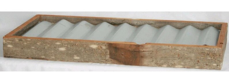 May include: A rectangular wooden soap dish with a light gray, wavy interior. The wooden frame has a natural, weathered appearance, showcasing the wood grain. The dish is designed to hold multiple bars of soap.