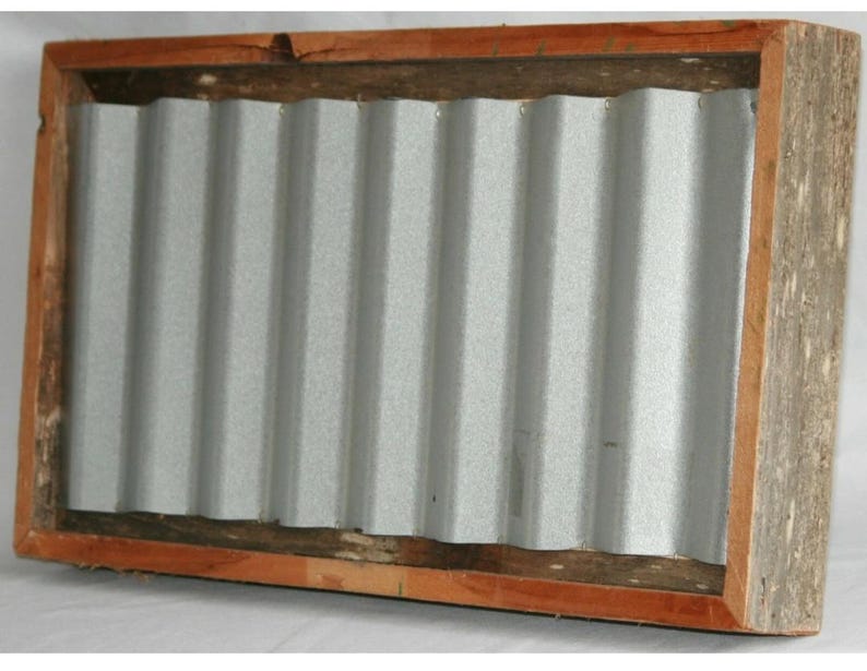 May include: A rectangular wooden frame with a corrugated metal insert. The frame is made of light brown wood with a darker brown trim around the metal. The metal is silver and has a ridged texture.