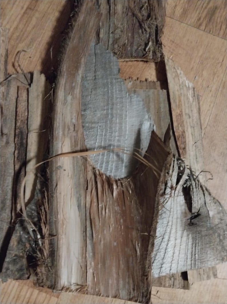 May include: Close-up of weathered wood pieces with varying shades of brown, gray, and tan. The wood has a rough, textured surface with visible cracks and splinters. Some pieces have a silvery-gray hue, while others are a warm brown.