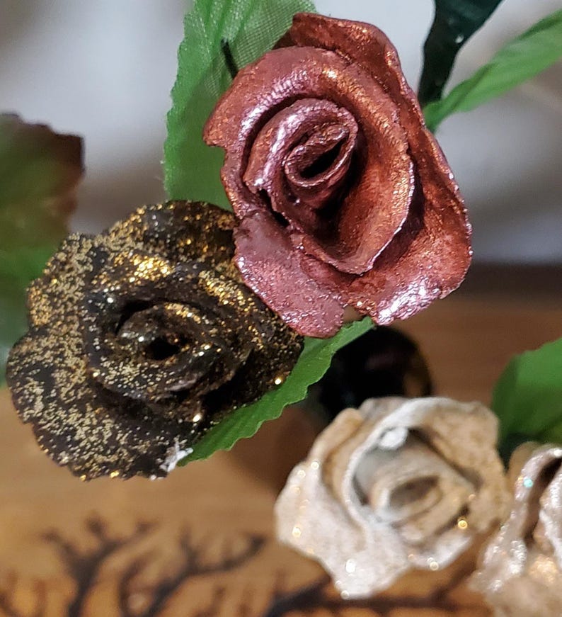 May include: Three artificial roses with glitter. The roses are in shades of gold, copper, and cream.