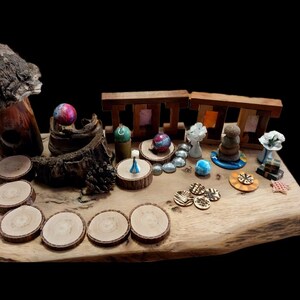 May include: A collection of handcrafted decorative items displayed on a wooden slab. The items include wooden coasters, miniature sculptures, colorful spheres, and small wooden structures. The background is black.
