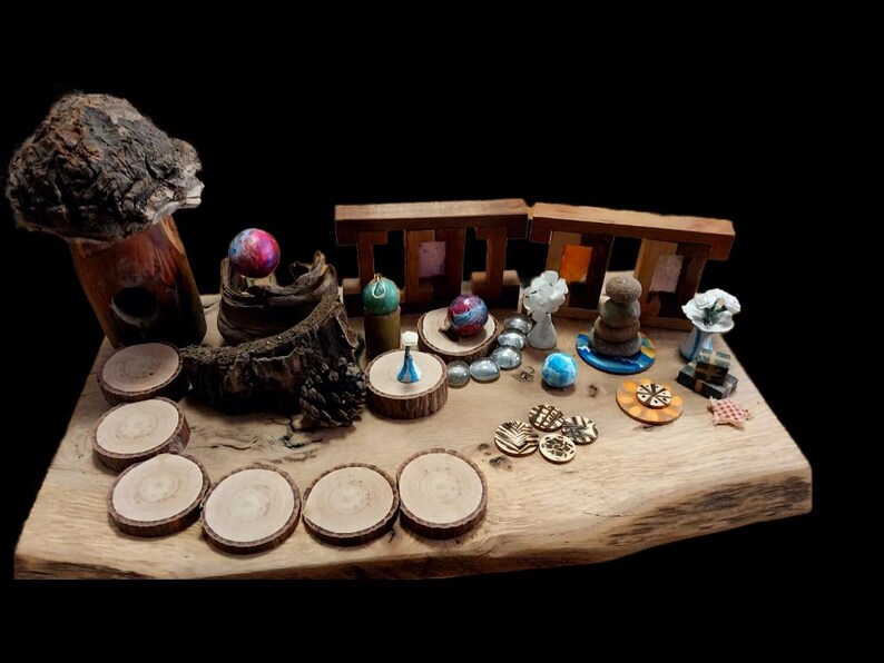 May include: A collection of handcrafted decorative items displayed on a wooden slab. The items include wooden coasters, miniature sculptures, colorful spheres, and small wooden structures. The background is black.
