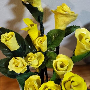 May include: A bouquet of yellow paper roses in a clear glass vase. The roses are made of paper and have a realistic appearance.