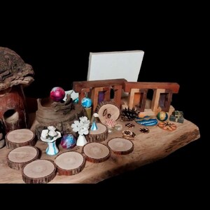 May include: A collection of miniature wooden and ceramic decorative items, including a mushroom house, Stonehenge replica, and small tree slices. The arrangement features various colors and textures, set on a wooden base.