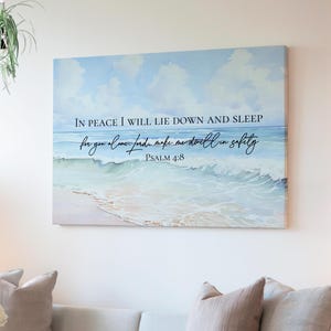 May include: A canvas wall art print with a blue ocean wave background and white sand. The print features a bible verse: "In peace I will lie down and sleep, for you alone, Lord, make me dwell in safety." Psalm 4:8