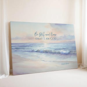 May include: A rectangular canvas wall art print featuring a watercolor-style ocean scene at sunset with soft pastel clouds. The text "Be Still and Know THAT I AM GOD" is centered in dark blue, with "PSALM 46:10" printed in the bottom right corner.