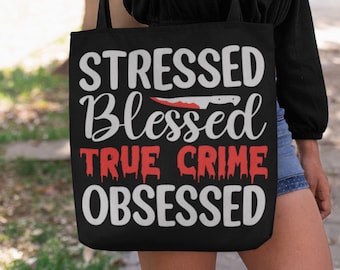 May include: Black tote bag with white text that reads "Stressed Blessed True Crime Obsessed". A red knife with blood dripping from it is above the word "Blessed".