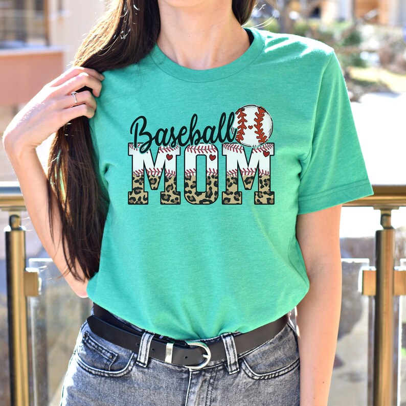 May include: A teal green t-shirt with a baseball graphic and the text "Baseball Mom" in black letters with a leopard print background.