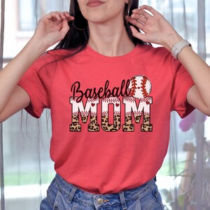 May include: Red t-shirt with a baseball graphic and the text "Baseball Mom" in white letters with a leopard print design.