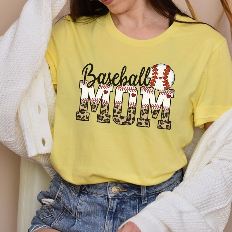 May include: Yellow t-shirt with the text "Baseball Mom" in black and red lettering with a baseball graphic and leopard print accents.