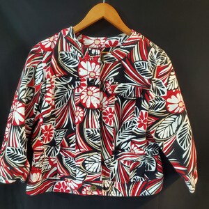 May include: A black, red, and white floral print jacket with a button closure. The jacket has a round neckline and long sleeves.