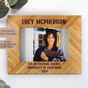 May include: A personalized bamboo photo frame with a graduation photo of a woman in a cap and gown. The frame has the text "LUCY MCPHERSON" at the top and "B.A IN POLITICAL SCIENCE UNIVERSITY OF CALIFORNIA 2024" at the bottom.