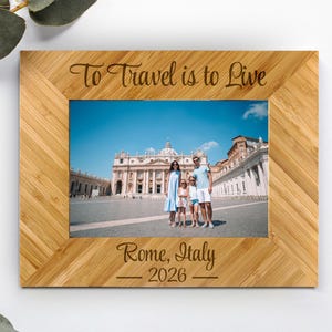 May include: A rectangular bamboo photo frame with a light brown wood grain finish. The top border is engraved with the text To Travel is to Live, and the bottom border features the text Rome, Italy 2026. A photograph of a family is inside.