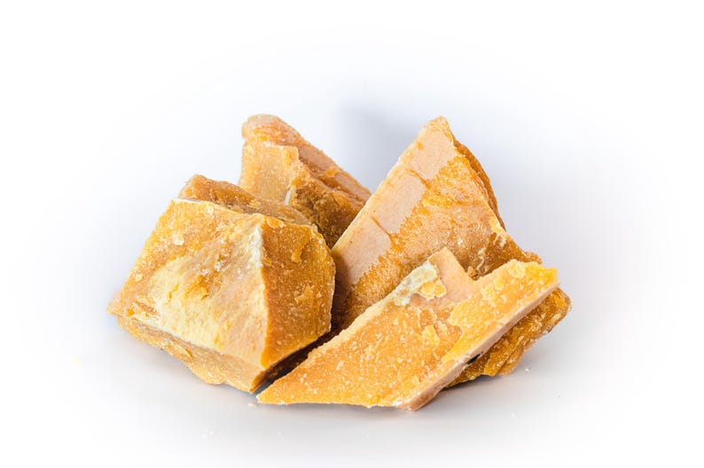 May include: A collection of irregularly shaped, golden-yellow beeswax blocks. The wax pieces have a rough, textured surface and vary in size, with some appearing triangular. The image is set against a clean white background, highlighting the natural color and texture of the wax.