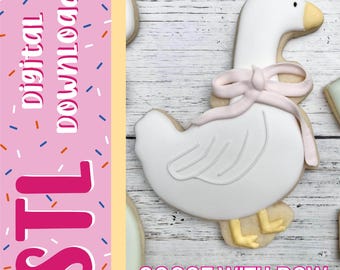 Può includere: Un biscotto bianco a forma di oca con un fiocco di glassa rosa chiaro intorno al collo, un becco giallo e zampe gialle. L'immagine include il testo digital download, STL e GOOSE WITH BOW su uno sfondo rosa con zuccherini colorati.