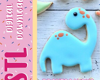 Può includere: Un biscotto a forma di Brontosauro azzurro con macchie arancioni e un occhio nero. L'immagine presenta una barra laterale rosa con il testo "digital DOWNLOAD" e "STL" in bianco e rosa, e la parola "BRONTOSAURUS" in rosa in basso.