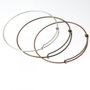 May include: Three bangle bracelets in different metal finishes: silver, bronze and copper. The bracelets are all open and have a spring clasp.