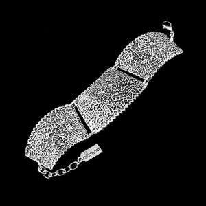 Puede incluir: Pulsera de plata con un diseño delicado e intrincado. La pulsera está hecha de cuatro secciones conectadas, cada una con un patrón único. La pulsera tiene un cierre y una pequeña etiqueta que dice "Crystalogy".