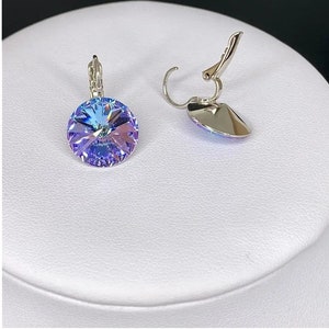 May include: A pair of silver clip-on earrings with a round, iridescent blue crystal.