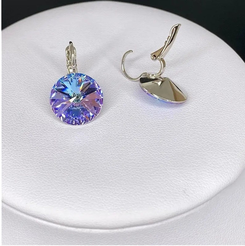 May include: A pair of silver clip-on earrings with a round, iridescent blue crystal.