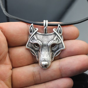 May include: Silver wolf head pendant necklace with intricate details and a black leather cord.